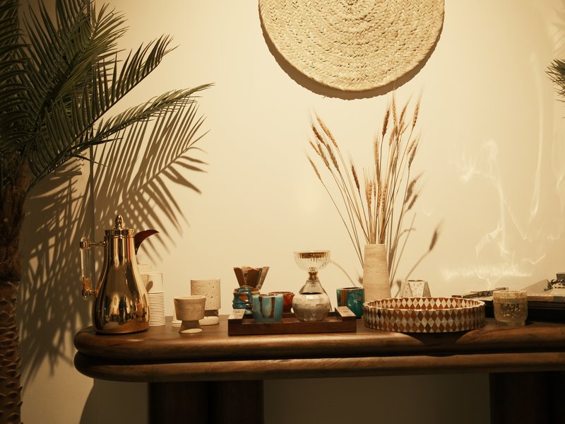 A wooden table adorned with various decorative items, including a coffee pot, vases, and dried plants.