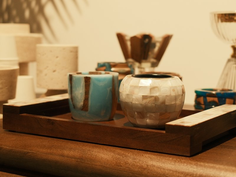 A wooden tray with two decorative pots, one blue and one white, surrounded by various craft items.