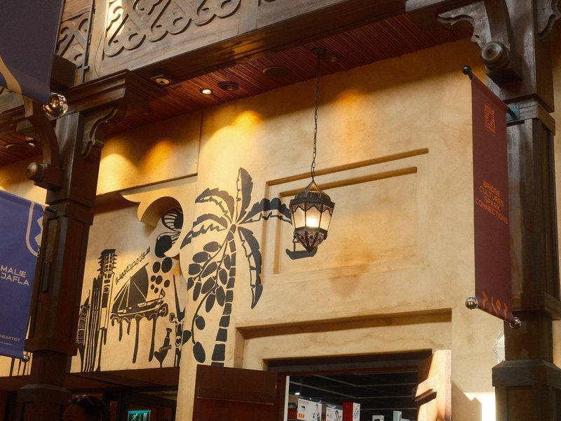 Decorative entrance of a restaurant with palm tree motifs and warm lighting.