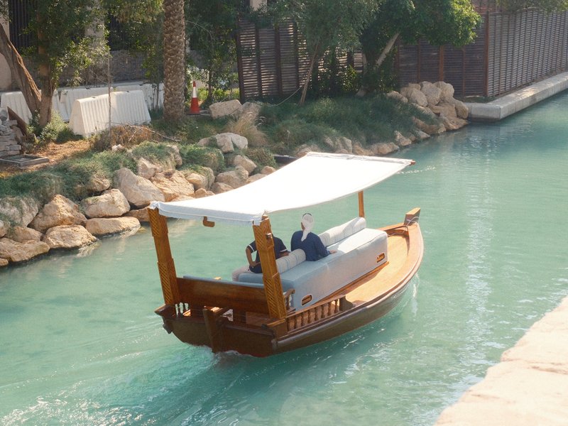 A traditional wooden boat gliding through a turquoise canal surrounded by lush greenery.