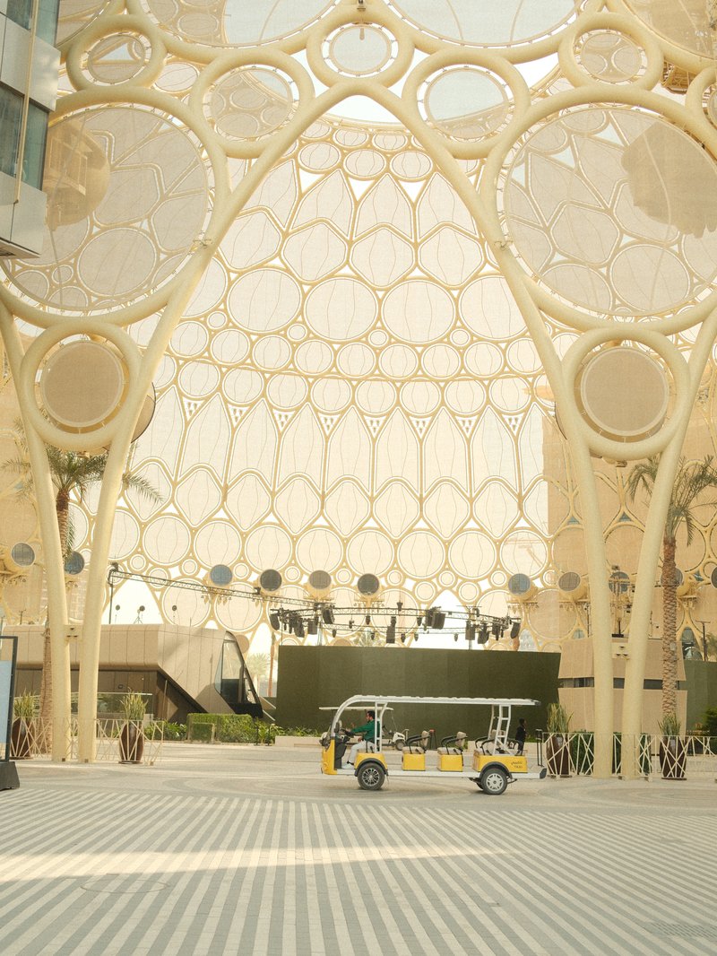 A modern architectural structure with a unique lattice design and a small vehicle in the foreground.