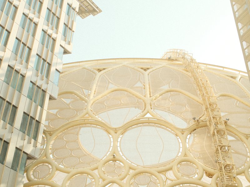 A modern architectural structure with a golden honeycomb design, surrounded by glass buildings.