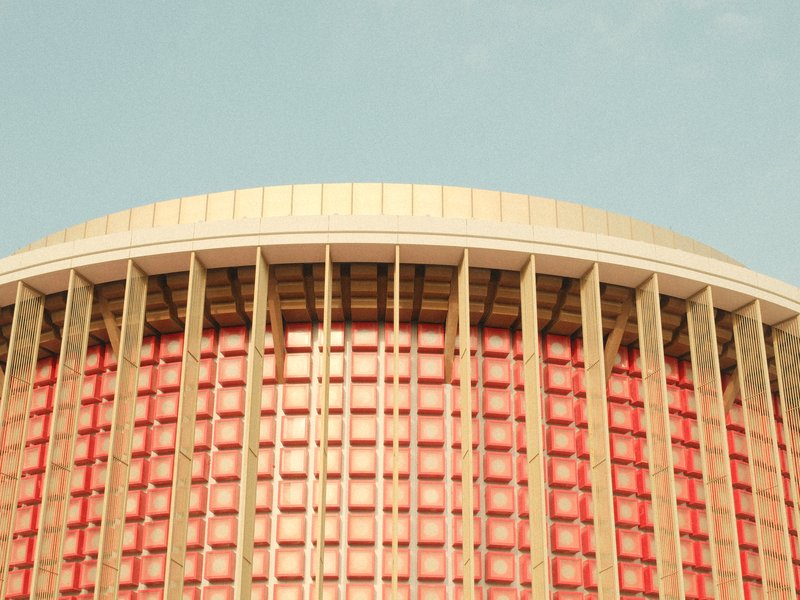 Close-up of a modern architectural building with a curved roof and vertical lines in warm tones.