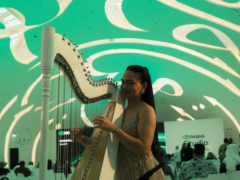 A woman playing a harp under a colorful, abstract ceiling design in a modern indoor setting.