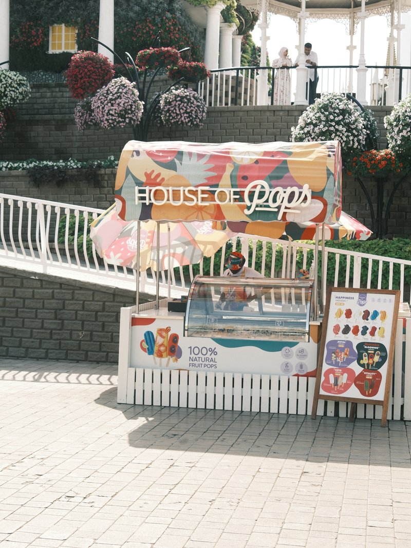 A colorful ice cream stand named 'House of Pops' with a variety of frozen treats displayed.