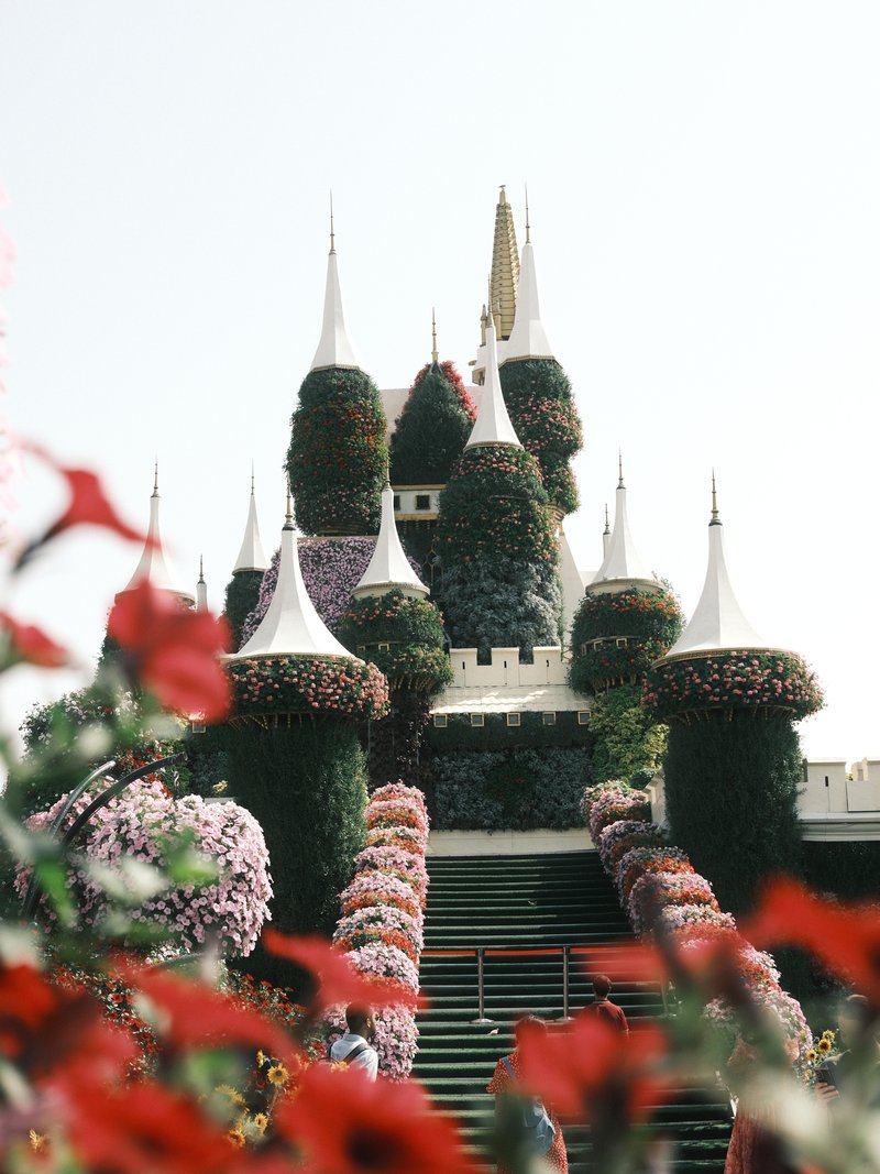 A floral castle with vibrant flowers in the foreground, showcasing intricate designs and spires.