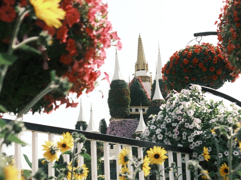 Colorful flowers in hanging baskets with a castle in the background under a cloudy sky.