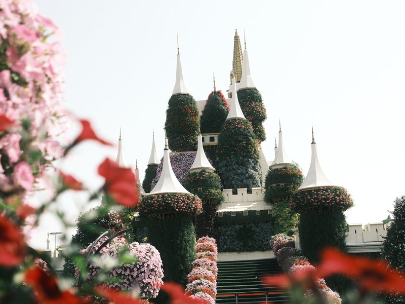A whimsical castle adorned with floral decorations, surrounded by vibrant flowers in the foreground.