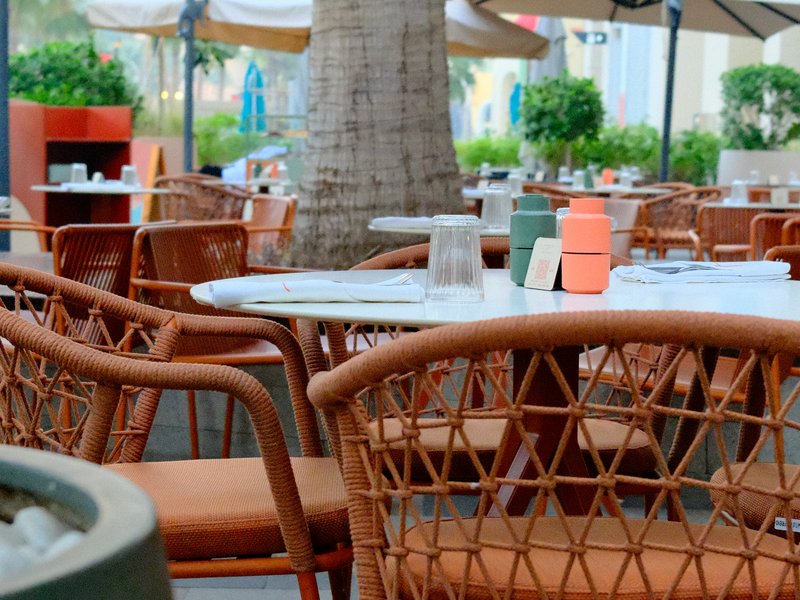 A cozy outdoor dining area with woven chairs and tables surrounded by greenery.