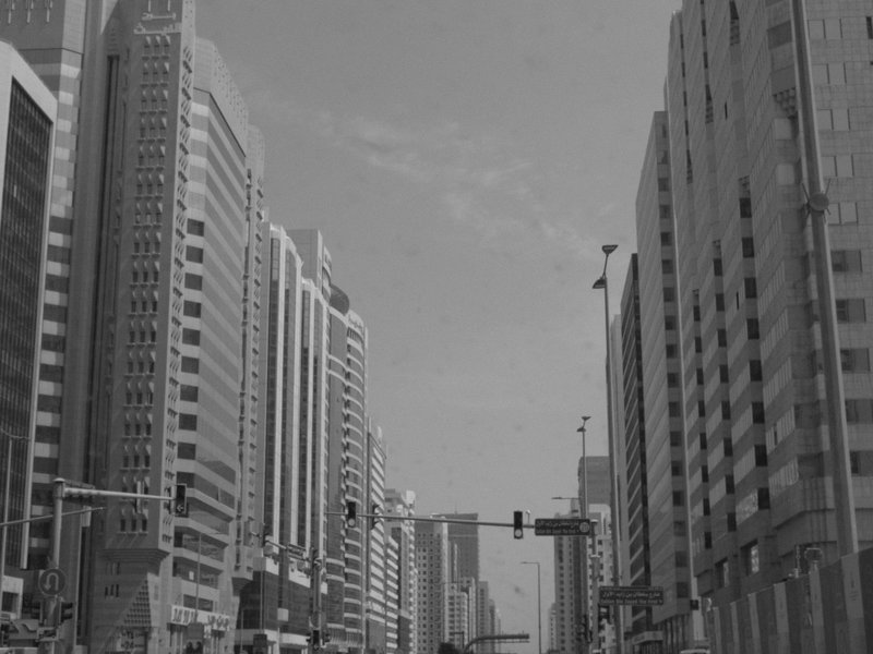 A bustling urban street lined with tall skyscrapers under a cloudy sky.