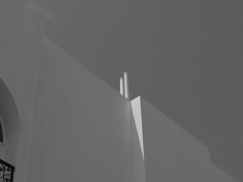 Abstract architectural detail with sharp lines and contrasting shadows against a clear sky.