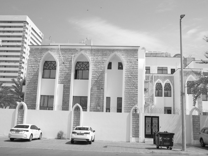 A historic building with arched windows and a modern city backdrop in black and white.