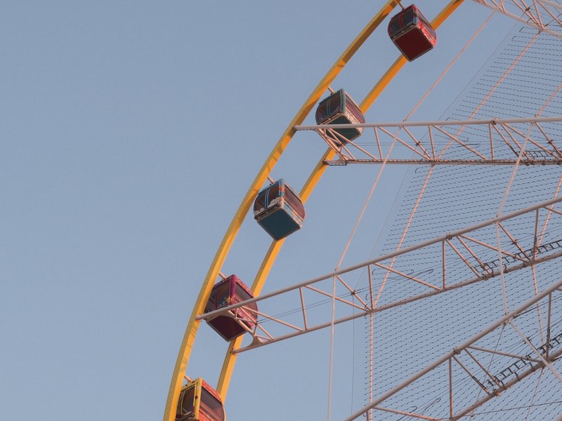 Close-up of a colorful ferris wheel against a clear blue sky.