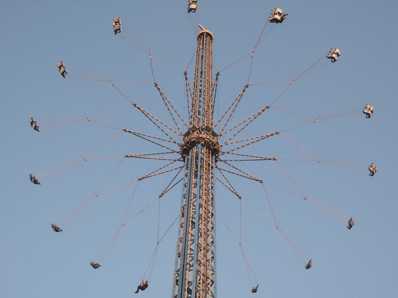 A tall amusement park ride with swinging seats against a clear blue sky.