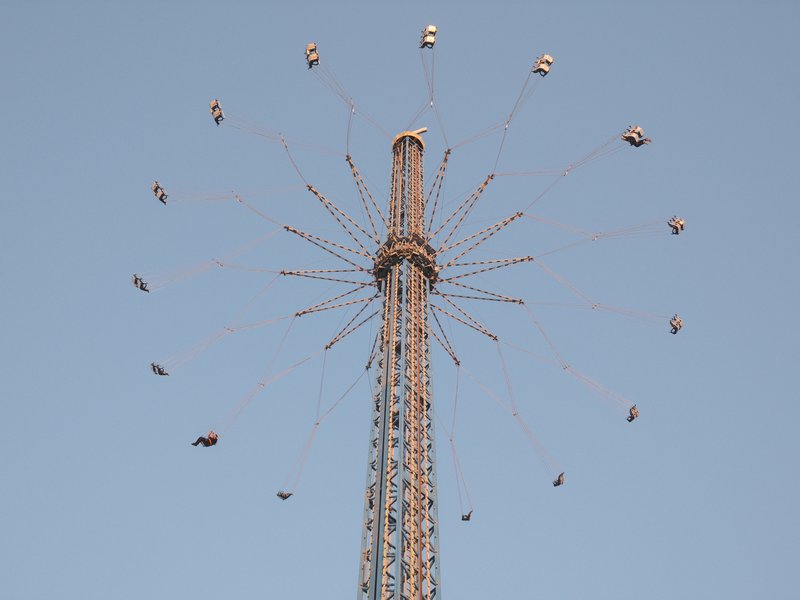 A tall amusement park ride with swinging seats against a clear blue sky.