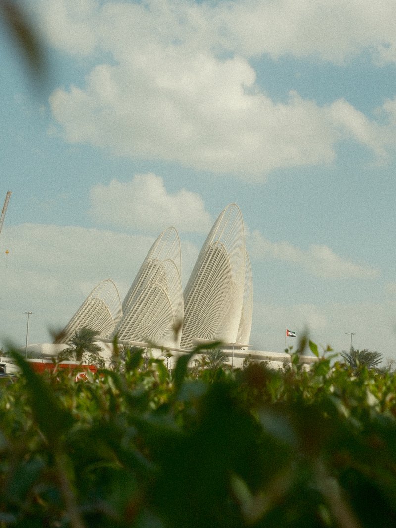 Three large, white architectural structures resembling petals against a cloudy sky.