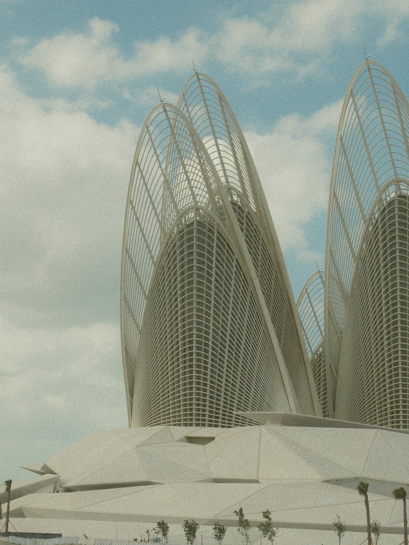 Close-up of a modern architectural structure with curved, pointed elements against a cloudy sky.