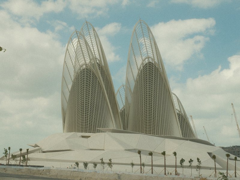 A modern architectural structure with tall, pointed features against a cloudy sky.