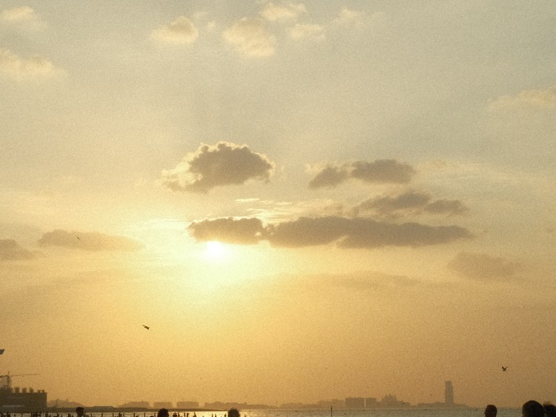 A serene sunset over a body of water with soft clouds and golden light illuminating the sky.