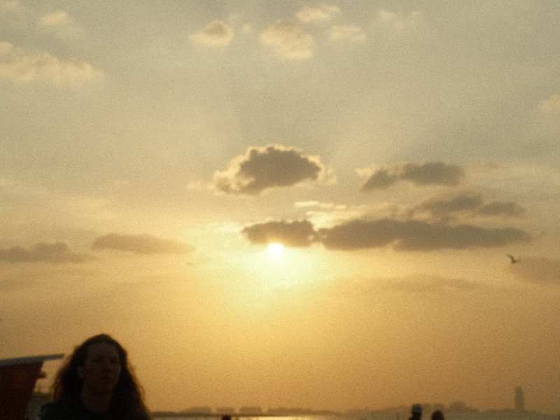 Silhouette of a person against a sunset with clouds and rays of light breaking through.