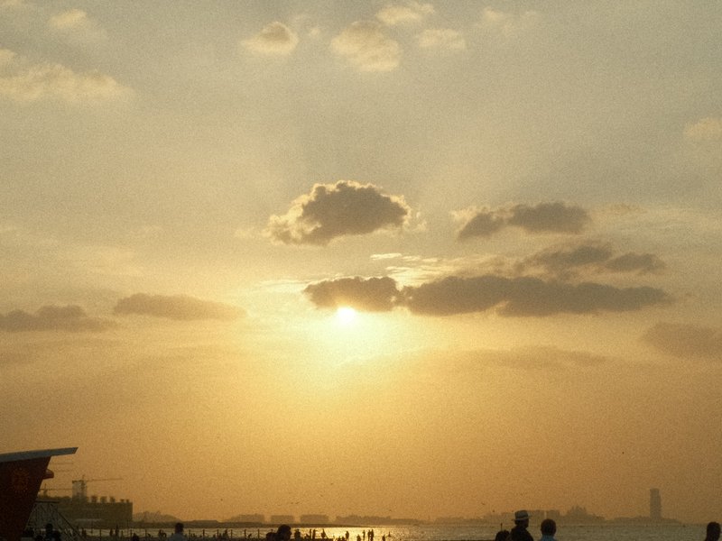 A sunset scene with clouds and silhouettes of people against a golden sky.