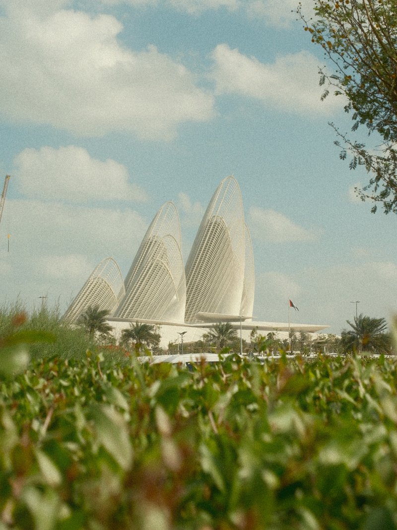 A modern architectural structure resembling lotus petals against a blue sky with clouds.