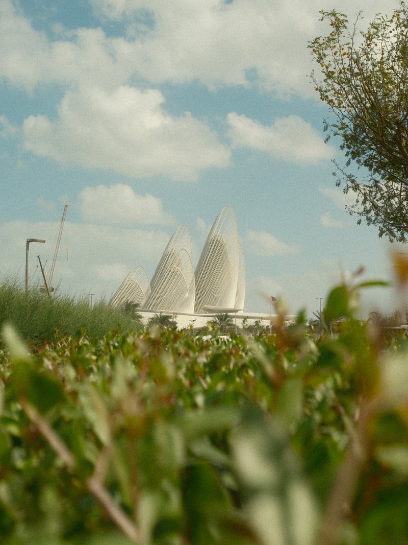 View of modern architectural structures resembling sails against a blue sky with fluffy clouds.