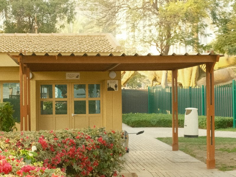 A wooden structure with a sloped roof, surrounded by colorful flowers and greenery.