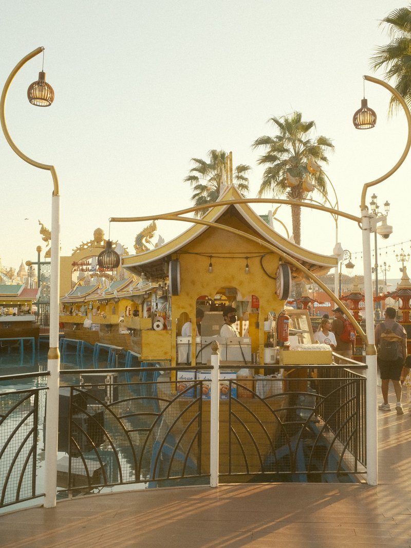A vibrant waterfront scene featuring a colorful boat and palm trees under warm sunlight.