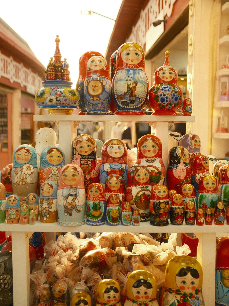 A display of colorful Russian nesting dolls arranged on a shelf in a market.