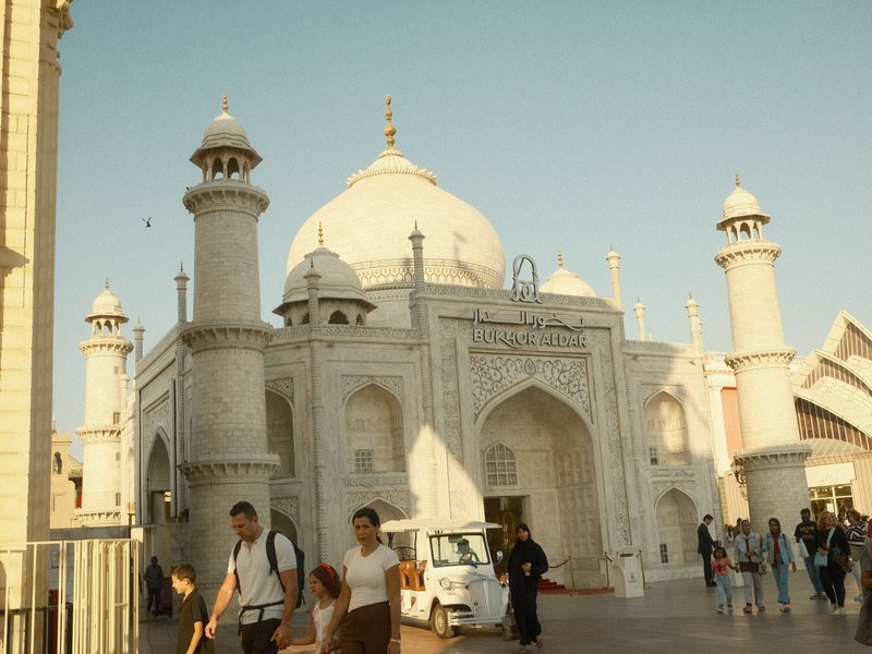 A white architectural structure resembling a mosque with domes and minarets, surrounded by people.