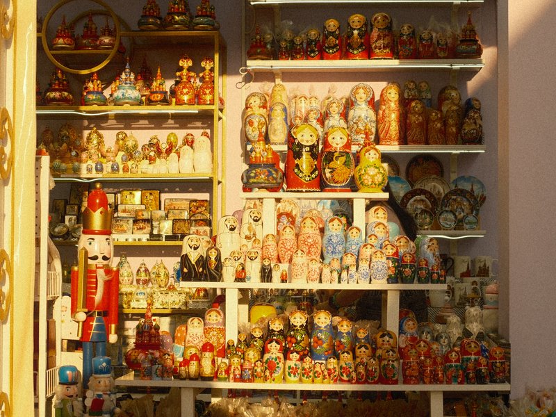 A display of colorful traditional dolls and figurines arranged on shelves in a shop.
