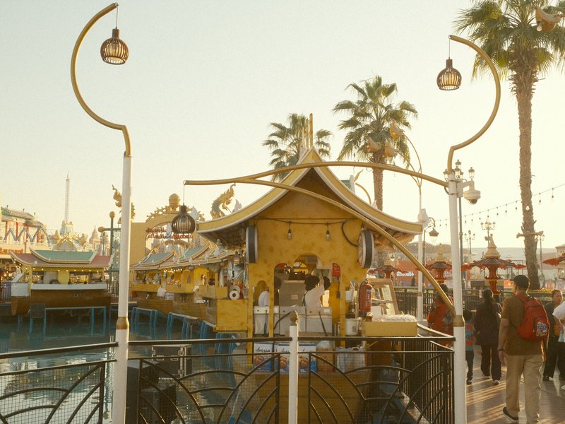 Colorful waterfront structure with palm trees and people during golden hour.