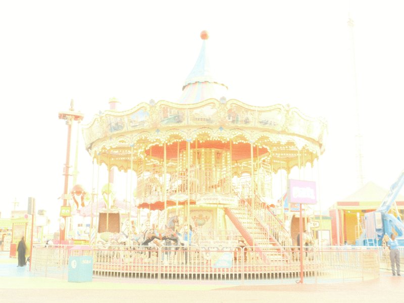 A bright, overexposed image of a carousel at an amusement park, with colorful decorations and a blue top.