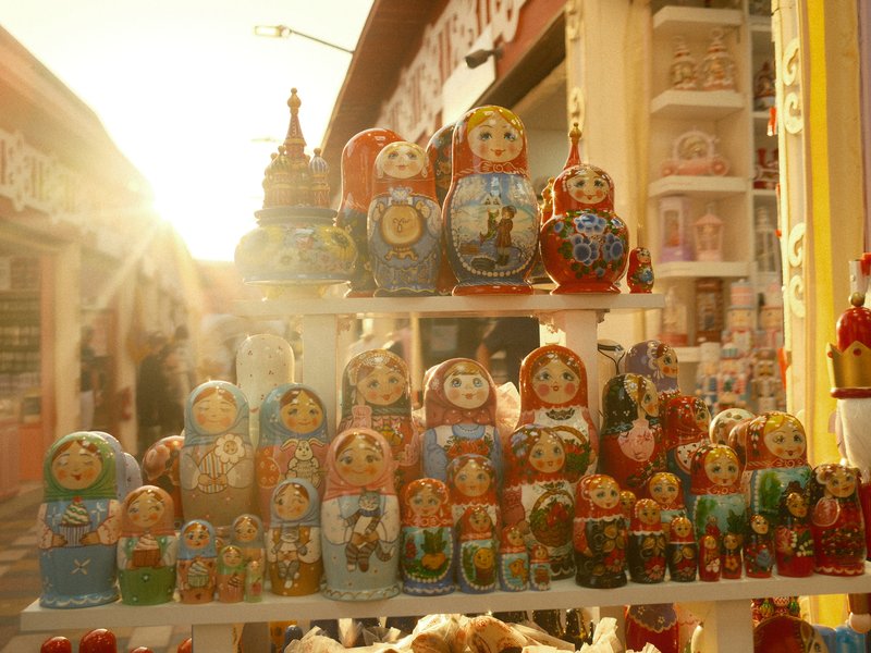 A collection of colorful matryoshka dolls displayed in sunlight, with a warm glow in the background.