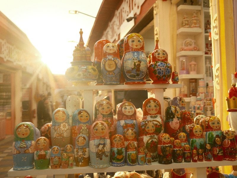 Colorful matryoshka dolls displayed on a shelf with sunlight shining through.