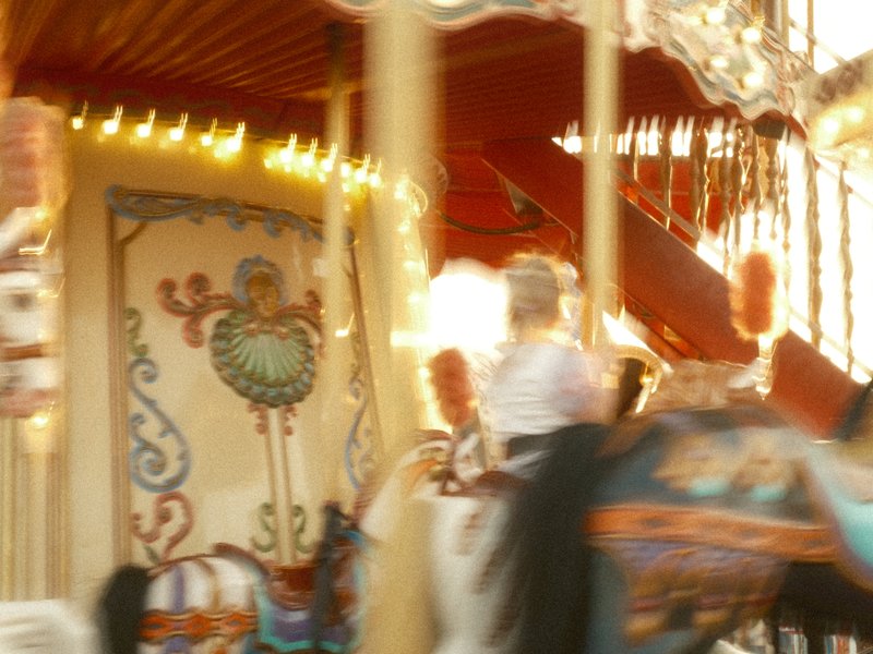 A blurred image of a carousel with colorful decorations and lights, capturing a sense of motion.