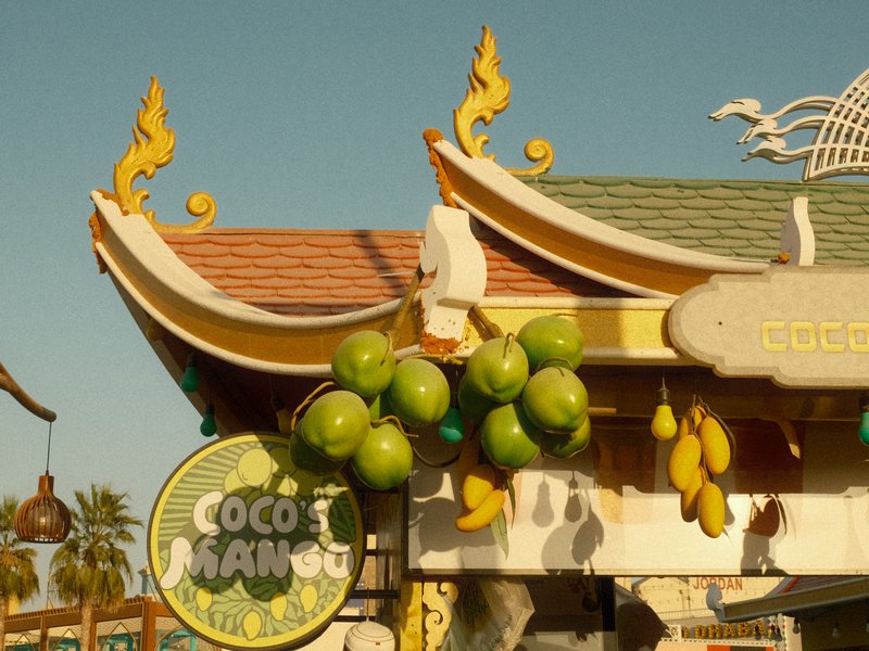 Colorful building with Asian-inspired architecture and green fruit decorations under a clear blue sky.