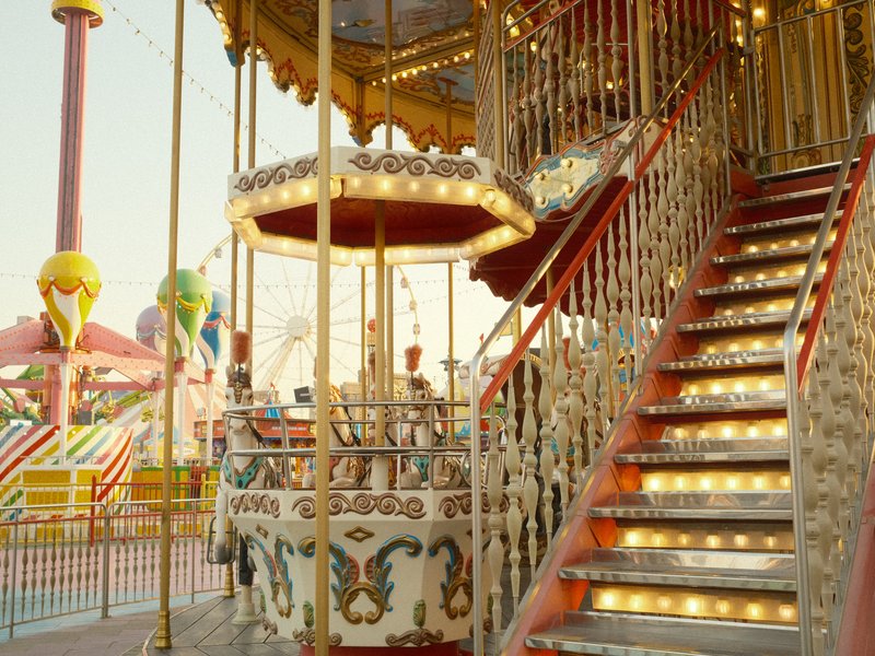 A colorful carousel with ornate decorations and illuminated stairs at a carnival.
