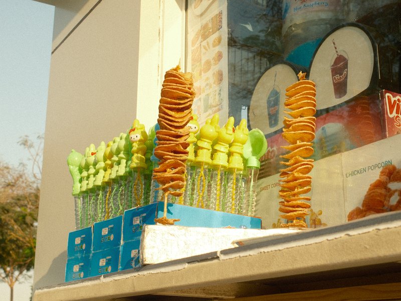 Colorful skewers of snacks displayed outside a shop, with a bright sunny atmosphere.