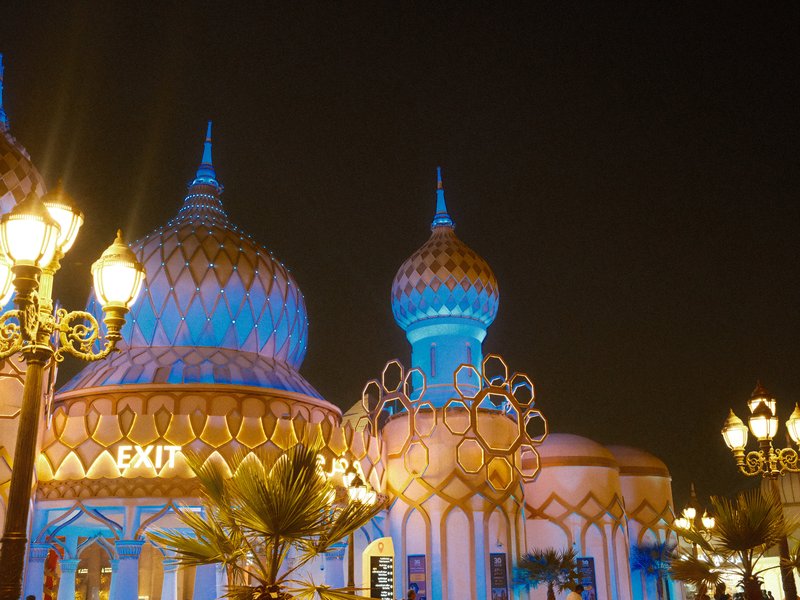 Colorful illuminated architecture at night with ornate domes and decorative lights.