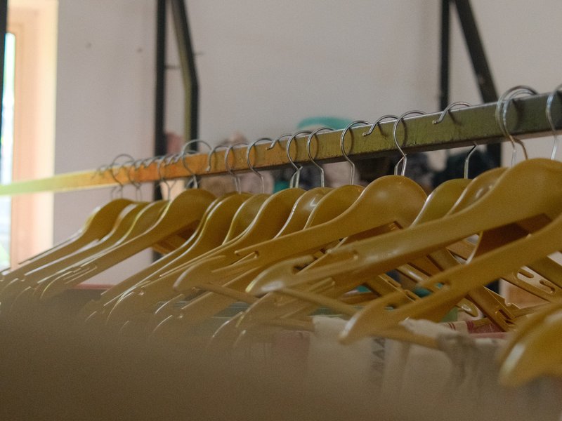 A row of wooden hangers on a rack in a bright indoor space.
