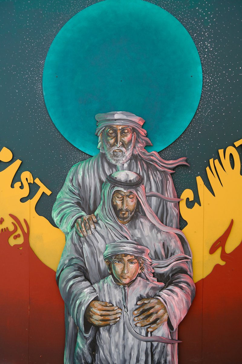 A mural depicting three figures in traditional attire against a colorful background with a large blue circle.