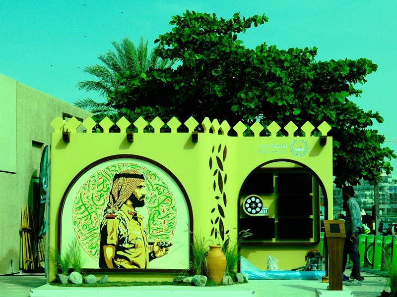 A vibrant mural of a man in traditional attire, surrounded by greenery and decorative architecture.