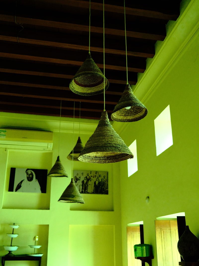 Hanging woven lamps in a brightly colored room with green walls and framed black-and-white photos.