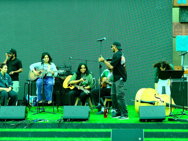 A group of musicians rehearsing on stage with guitars and microphones in a vibrant setting.