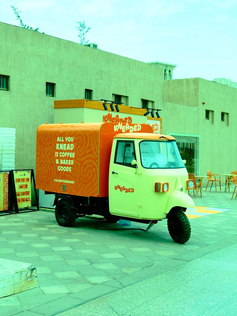 A colorful food truck parked in an urban setting with outdoor seating nearby.