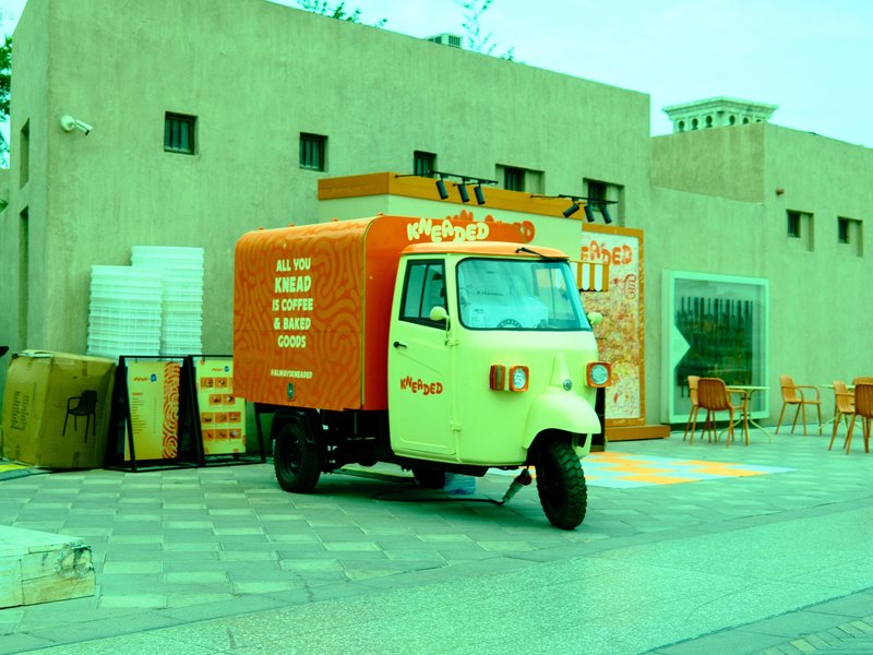 A colorful food truck parked in an urban setting with vibrant signage and a tiled floor.