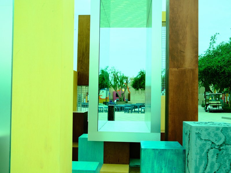 Abstract sculpture with colorful geometric shapes and reflections in a public space.