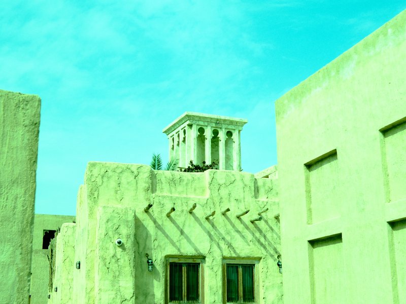 A view of buildings with a green tint, featuring a tower and blue sky in the background.